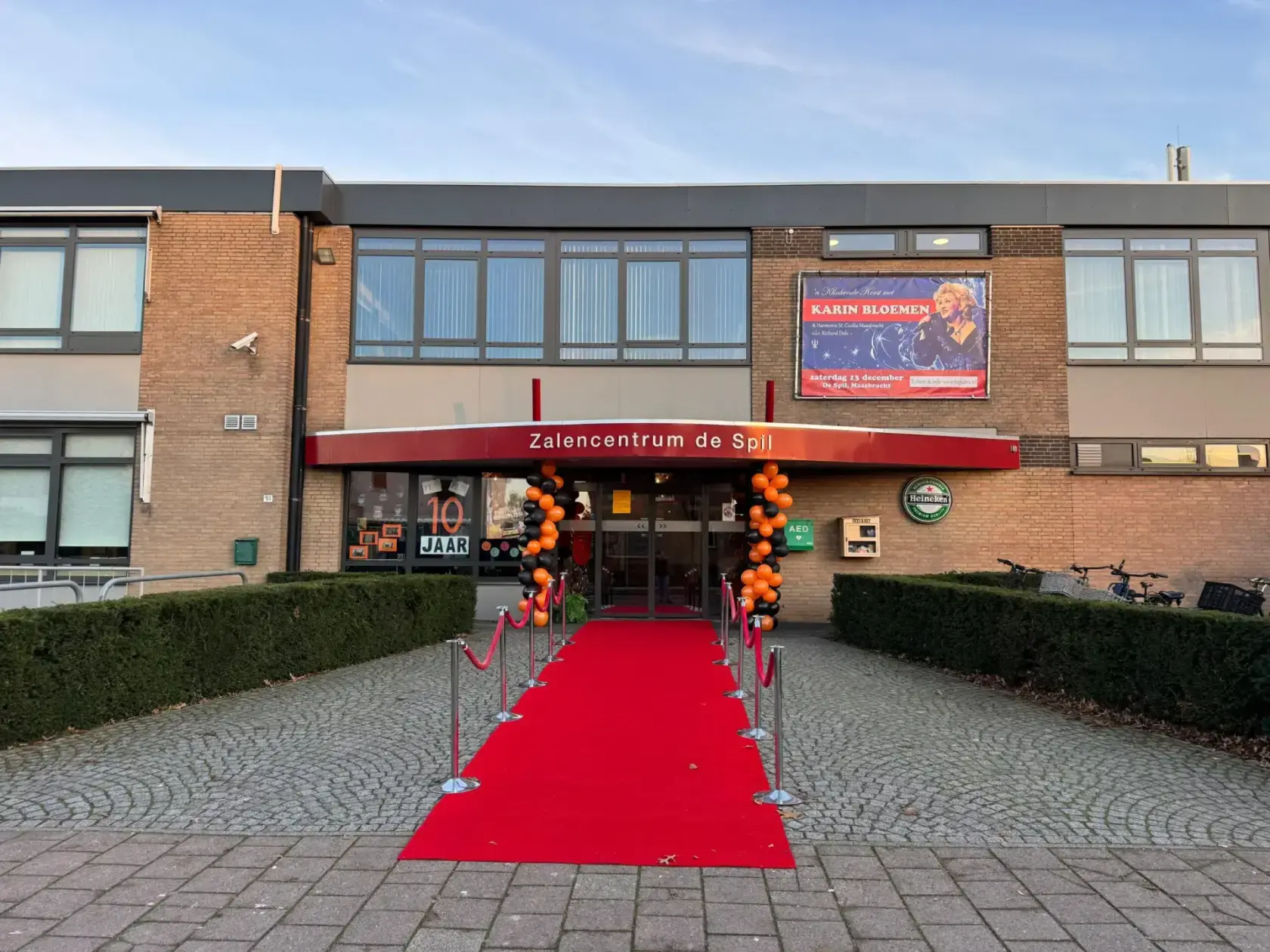 De entree van Zalencentrum De Spil met de rode luifel en de rode loper